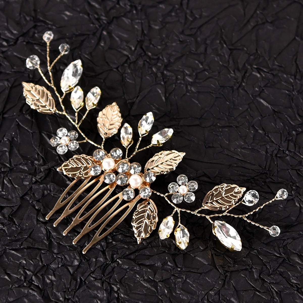 Une délicate pièce de cheveux de mariée en or et cristal avec des feuilles et des éléments scintillants.
