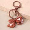 A brown leather coffee cup keychain featuring a heart design and a spoon, attached to a round leather keyring.
