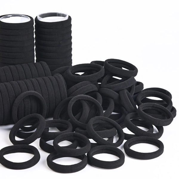 A pile of black elastic hair bands and hair ties.