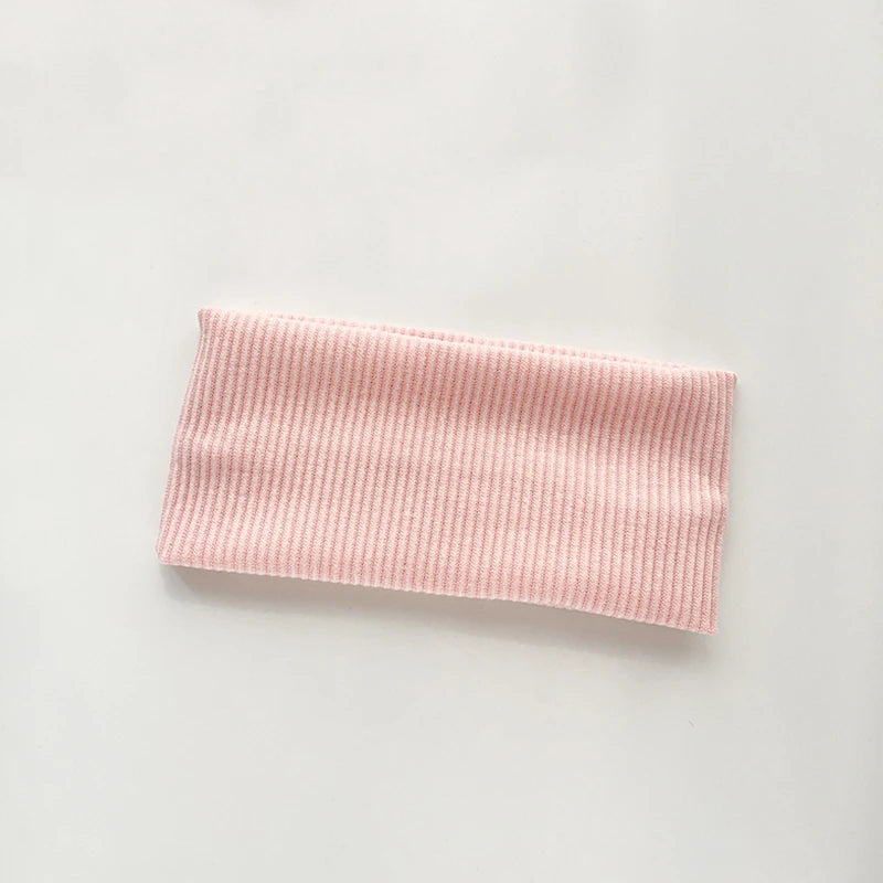 A pink knitted sports headband with vertical ribbing.