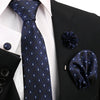 Dunkelblaue gemusterte Krawatte und Accessoires vor schwarzem Sakko und weißem Hemd.