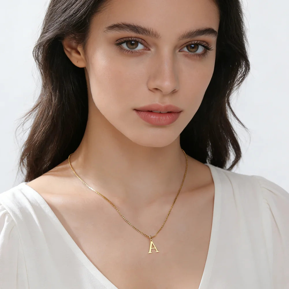 A woman wearing a gold initial letter necklace with a white top