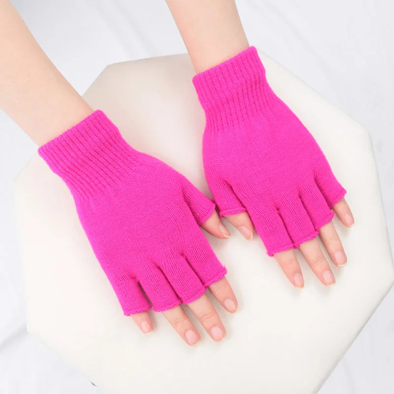 A pair of bright pink knit half finger gloves being held by hands against a white background.