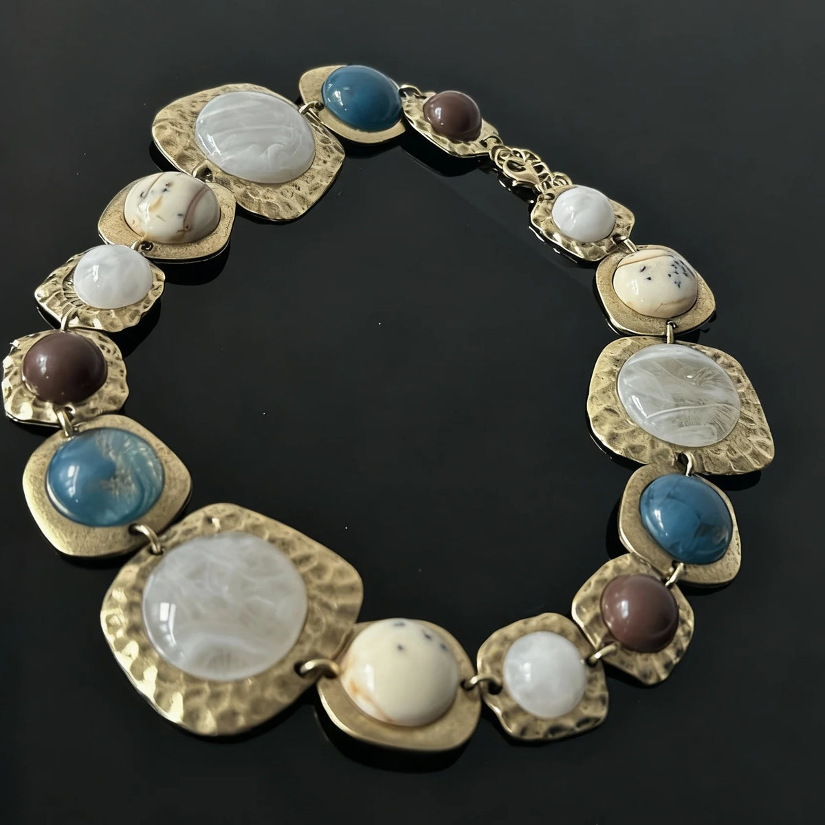 Boho gold plated resin statement choker necklace featuring round beads in blue, white, and brown tones.