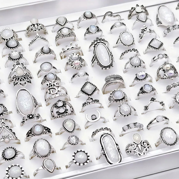 A collection of silver and white stone charm rings displayed in a white tray.