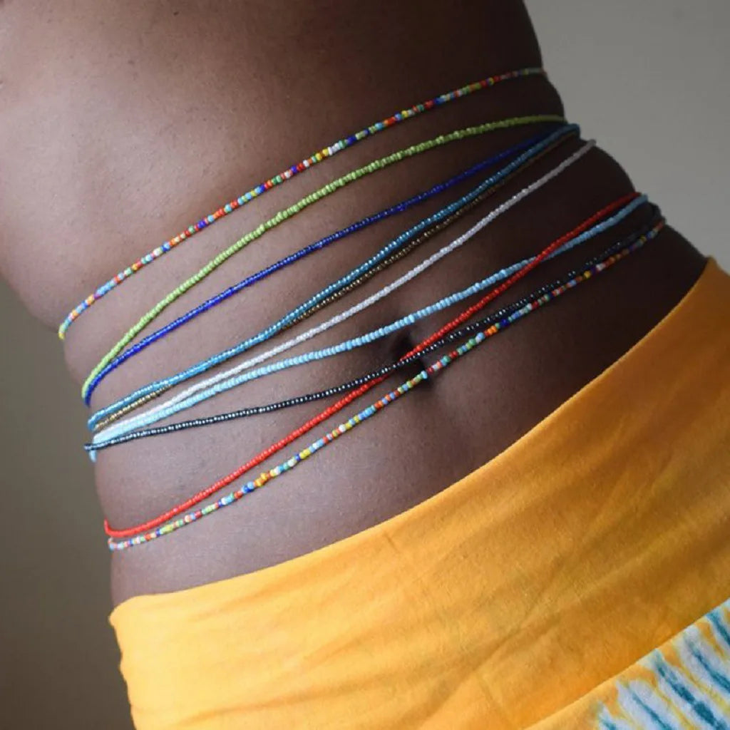 Primer plano del torso de una modelo mostrando varias cadenas de cuentas coloridas envueltas alrededor de la cintura.