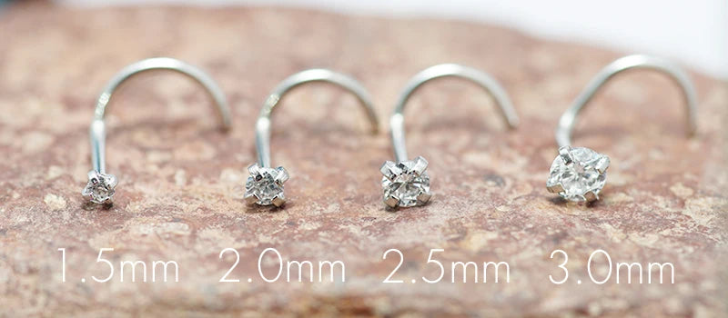 A row of stainless steel nostril studs in various sizes (1.5mm to 3.0mm) with crystal accents.