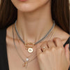 A close-up of a multilayered gold necklace featuring various charms including a star eye pendant and a small ring.