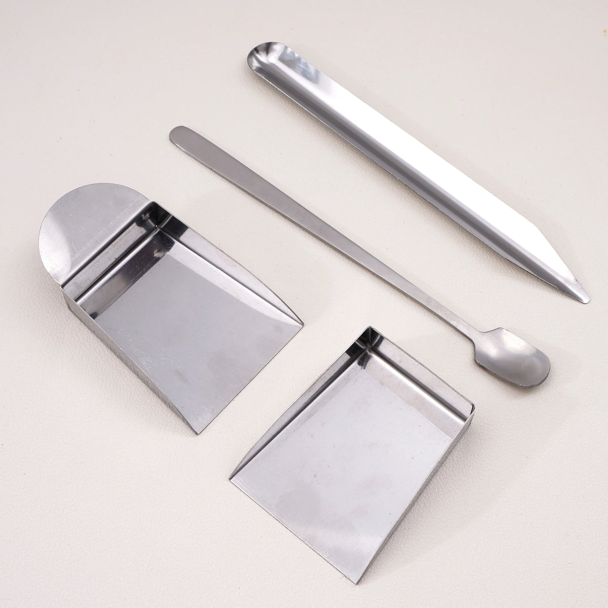 A set of stainless steel bead shove tools for jewelry making, including a flat tool and a pointed tool.