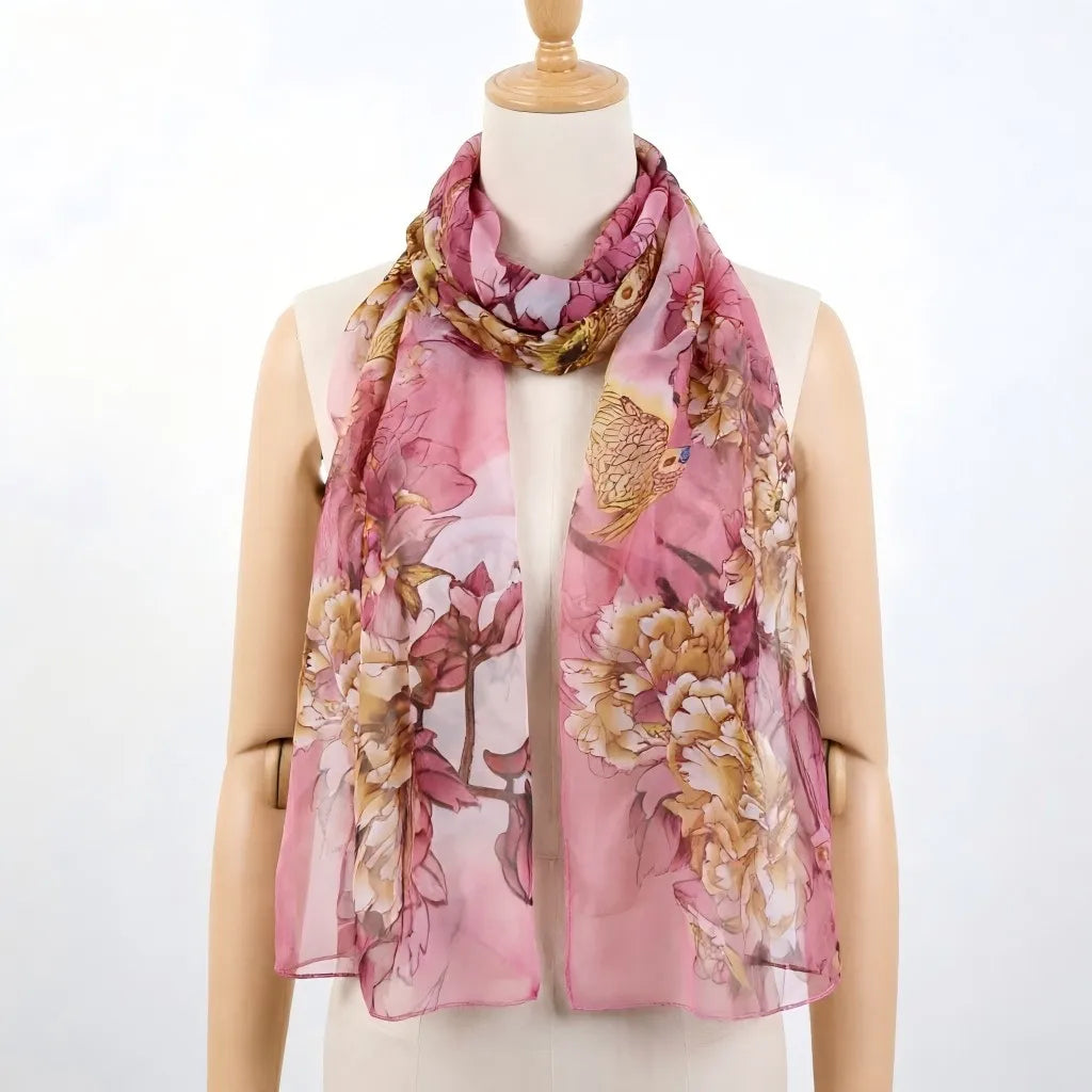Écharpe de soie florale rose avec des accents or et crème drapée autour du cou d'un mannequin.