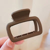 A close-up of a single square lightweight hair claw clip in a matte olive green color being held by a hand.