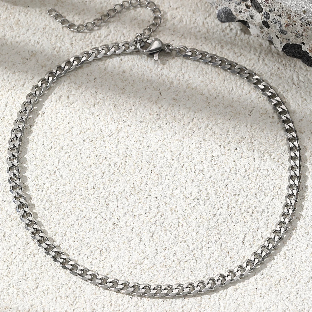 A silver multi-chain stainless steel anklet laid on a light surface.