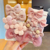 A collection of pink and mauve flower bow hair ties for girls, featuring various textures and shades.