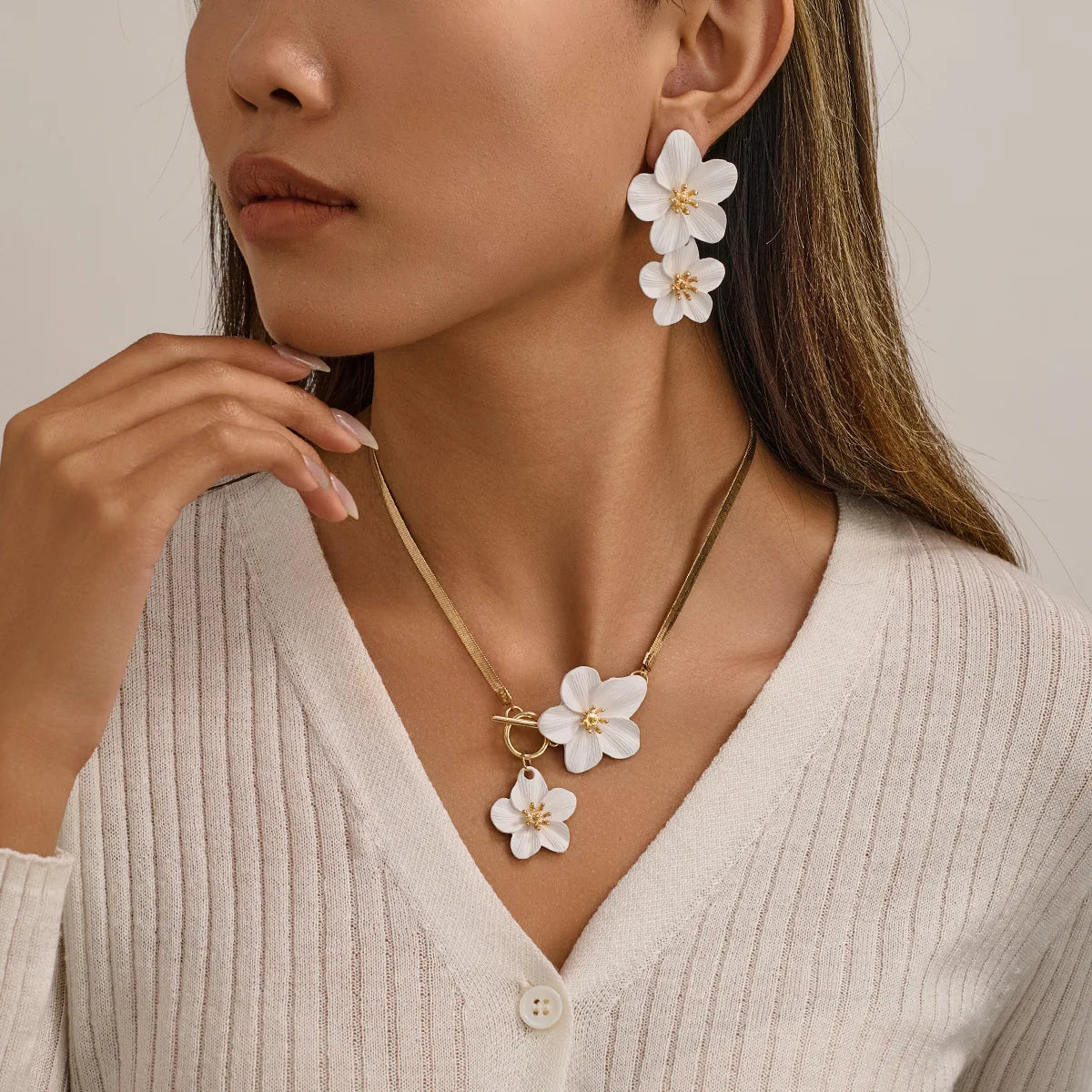 A close-up of a woman wearing a gold floral pendant necklace and matching earrings on her neck and ears.