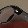 A close-up view of black oversized fashion pilot sunglasses with a gold-toned hinge detail.