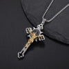 A silver and gold retro Christian cross amulet necklace resting on a dark gray stone.
