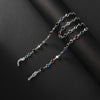 Una delicada cadena de plata con cuentas de cristal de varios colores, incluyendo azul, rojo y verde, mostrada contra un fond