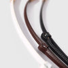 A close-up of a skinny leather belt featuring an adjustable gold buckle, shown in white and brown colors.