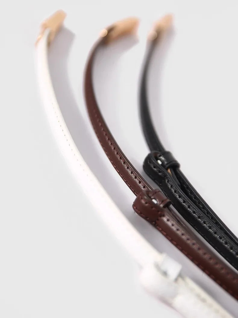 A close-up of a skinny leather belt featuring an adjustable gold buckle, shown in white and brown colors.
