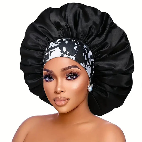 A woman wearing an extra large satin sleep bonnet with an elastic band in black and white floral print.