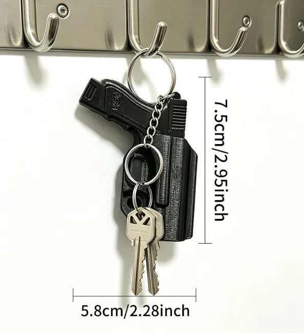 A black tactical pistol keychain featuring a detachable holster and a small metal key.