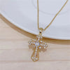 A gold-toned vintage cross pendant necklace with clear stones displayed on a white background.