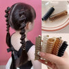 A set of rubber braided ponytail holders and scrunchies in various natural and black shades shown on a plate.
