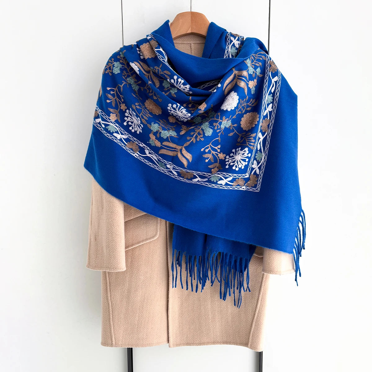 A royal blue luxury floral scarf with gold and white embroidery draped over a beige top.