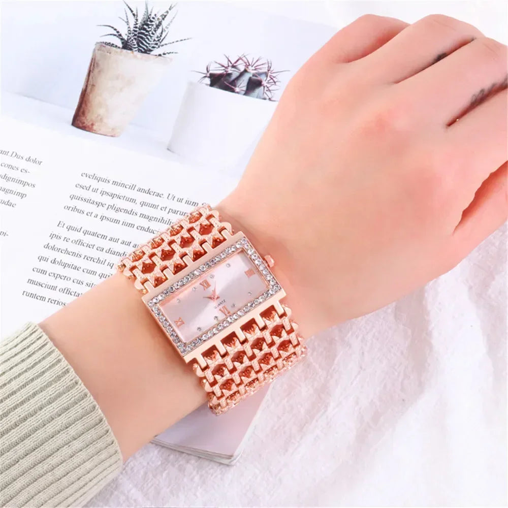 A close-up of a fashion quartz diamond watch with a gold stainless steel bracelet on a wrist next to some paper and a succule