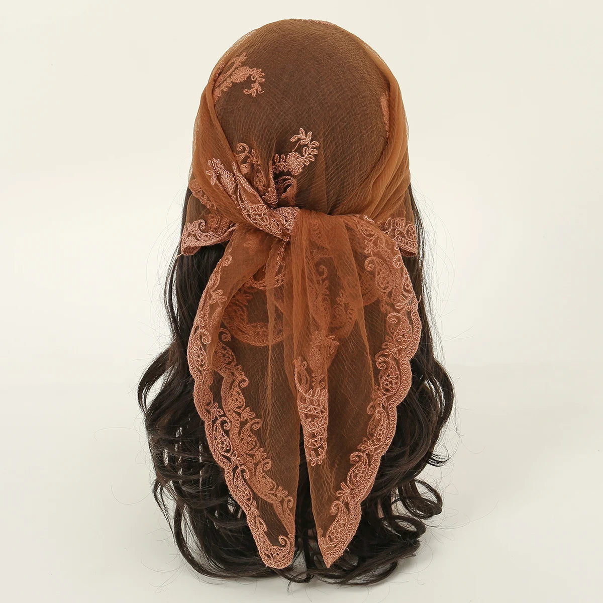 A close-up of a brown floral embroidered lace bandana headscarf tied around dark hair.