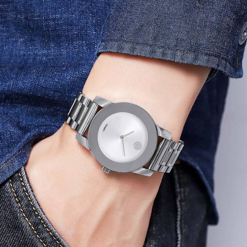 A silver minimalist quartz wristwatch worn on a wrist, paired with a dark blue denim shirt.