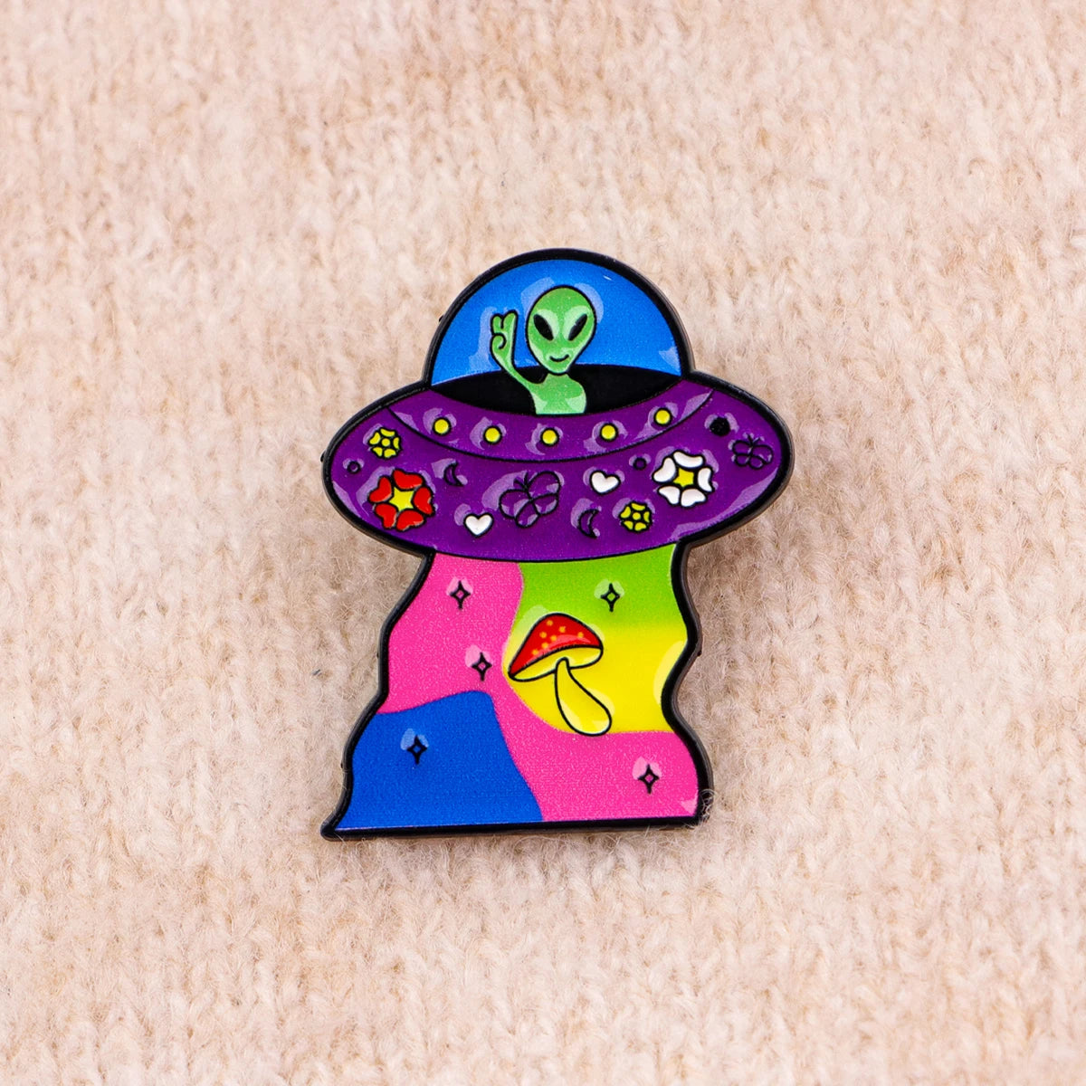 A colorful enamel pin featuring a green alien head inside a purple, textured bowl shape with mushroom accents.