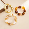 Un set de bracelets de charme vintage en résine acrylique bohème avec des perles dorées et ambrées.