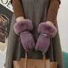 A pair of purple plush wrist gloves worn by a person, held against a gray coat.
