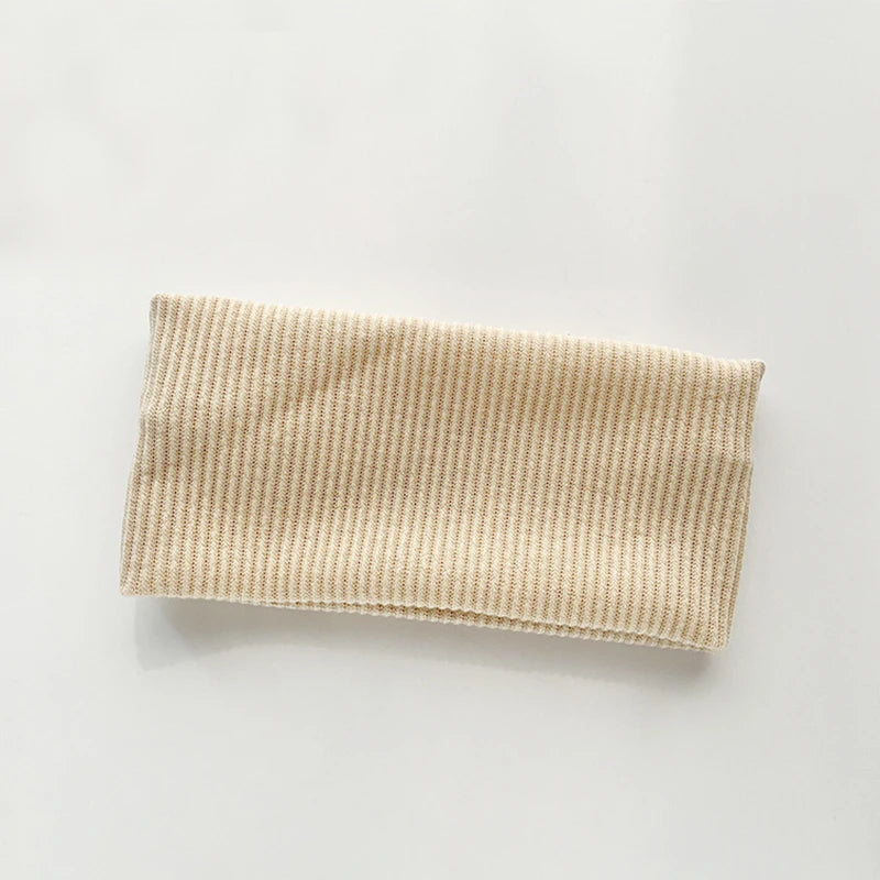 A beige knitted sports headband is shown flat against a white background.