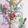A collection of sweet resin animal dog keychains hanging from a green fir branch.