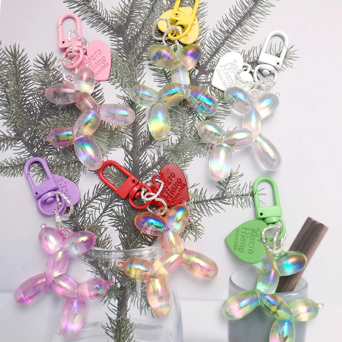 A collection of sweet resin animal dog keychains hanging from a green fir branch.