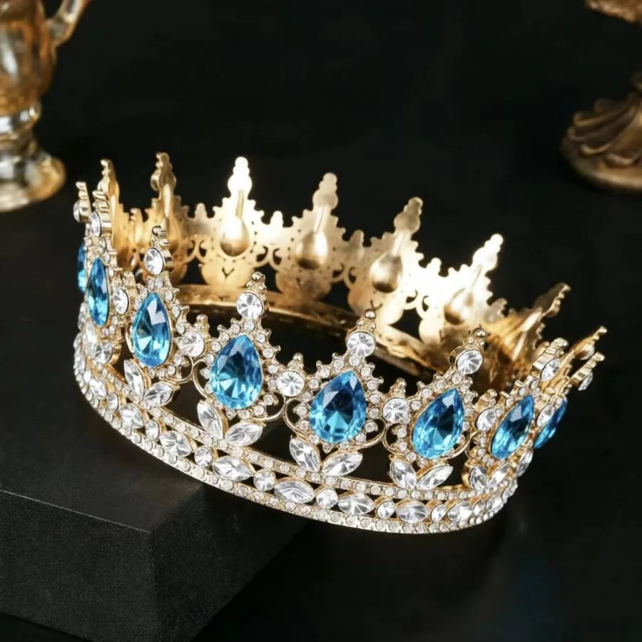 Couronne de diadème en strass de cristal or avec des gemmes bleues posée sur une surface sombre.