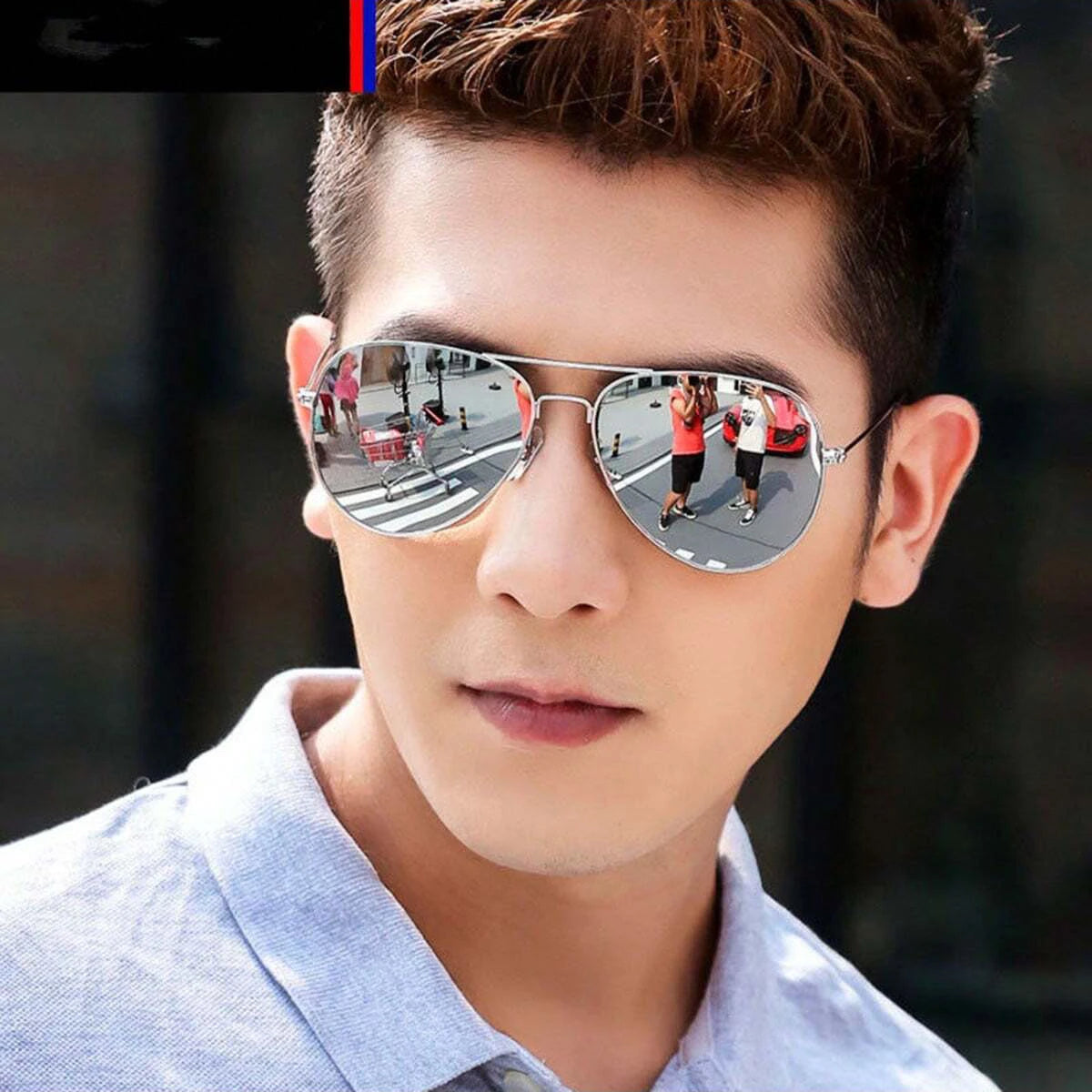 A young man wearing silver aviator sunglasses outdoors.