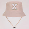 A beige sun hat with a large white letter X embroidered on the front and a light tan strap.
