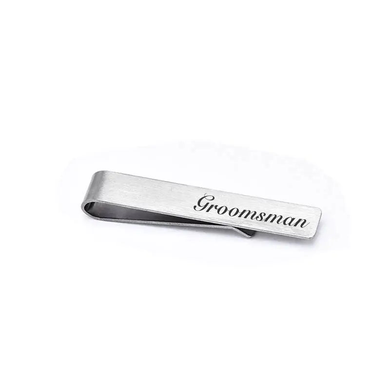 A brushed stainless steel men's tie clip engraved with the word groomsman.