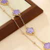Elegant gold five-leaf clover anklet with purple gemstone beads displayed on a wooden surface.