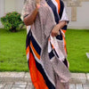 Eine Person trägt ein schwarz-weiß gemustertes Kaftankleid mit orangefarbenen Akzenten im Freien.