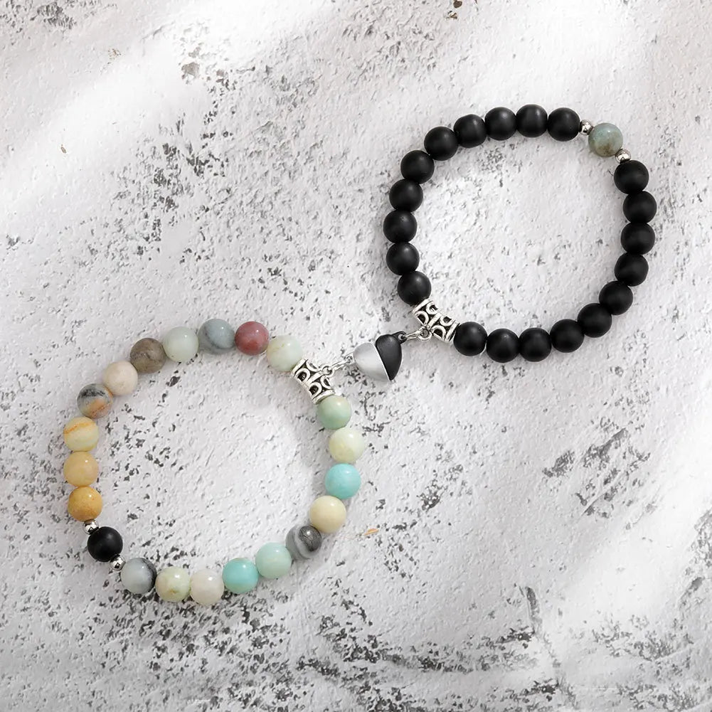 A pair of natural stone heart couple bracelets featuring black and light colored stones on a white background.