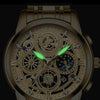 A close-up of a gold-toned men's stainless steel quartz wristwatch with an intricate mechanical dial and luminous features.