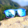 Gradient square frame polarized sunglasses resting on a rock with a scenic outdoor background