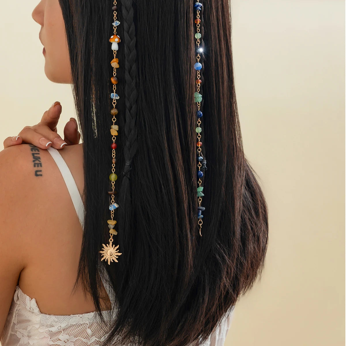 A close-up of long dark hair adorned with a bohemian sun moon tassel hair headdress featuring multicolored beads and a gold s