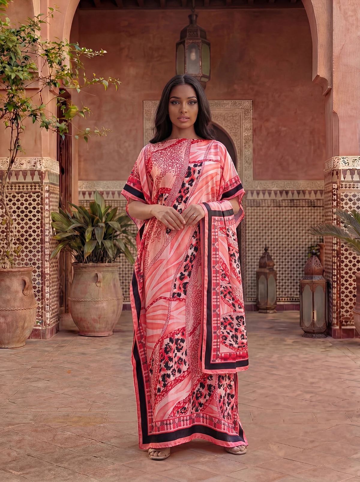 Une femme portant une caftan abaya imprimé léopard zèbre rose et noir dans une cour voûtée.