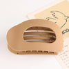 A beige flat circular hair clip set is shown resting on a piece of paper with a line drawing of a bird.