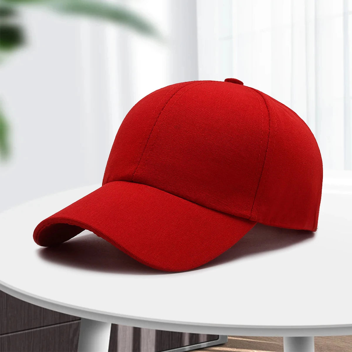A solid red unisex cotton curved visor hat is displayed on a white table.